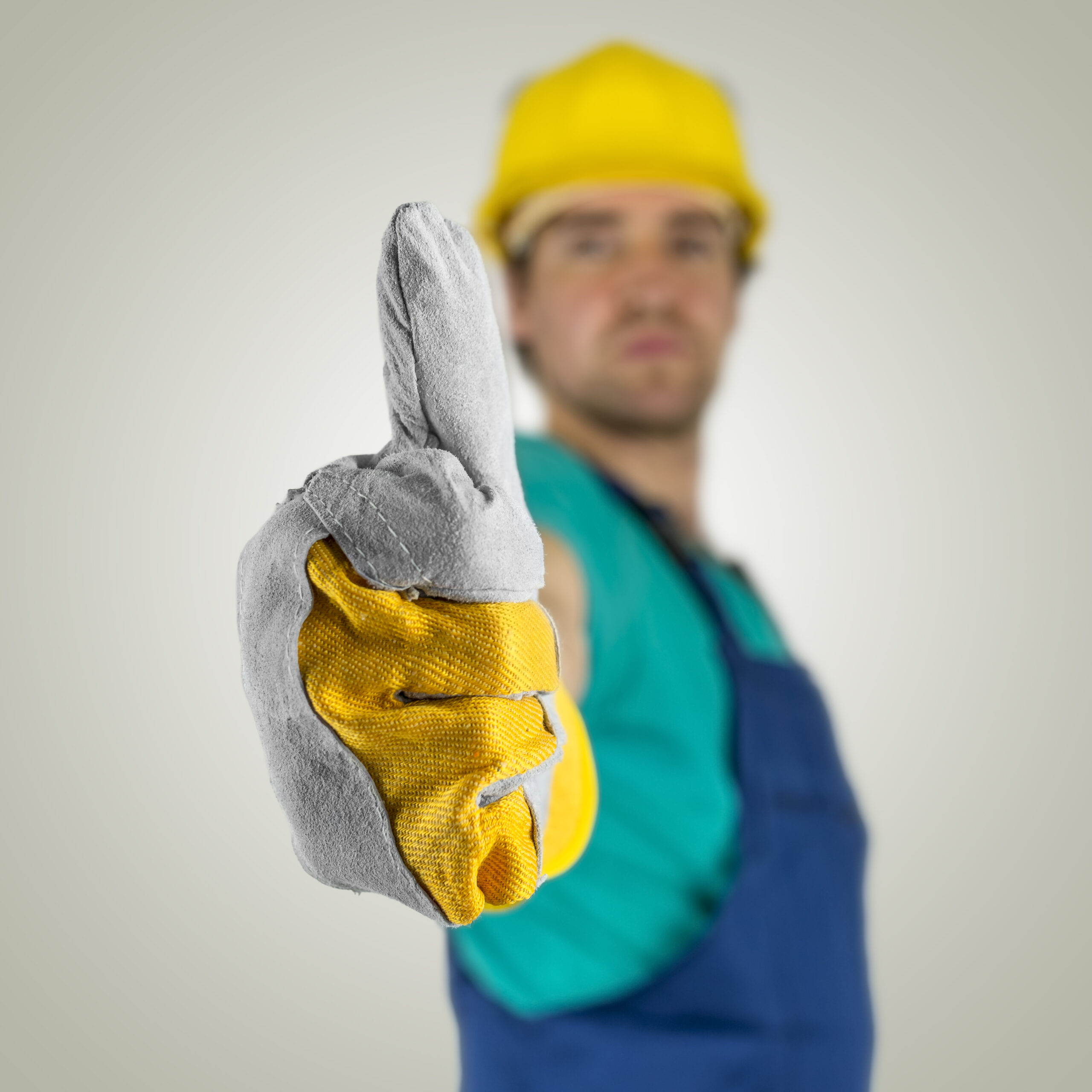 Young construction worker showing thumbs up sign.